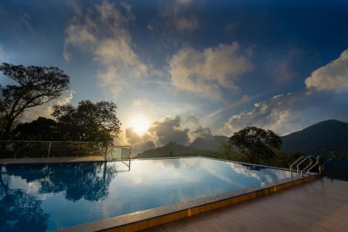 een zwembad met een regenboog aan de hemel bij Camelot Resort in Munnar