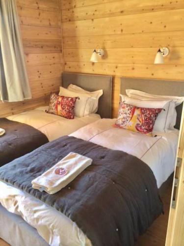 deux lits dans une chambre aux murs en bois dans l'établissement Lovely 4 bedroom apt ski-in ski-out with sauna, aux Houches