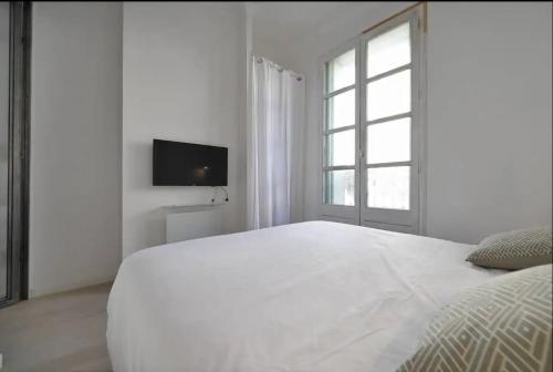 a white bedroom with a white bed and a window at Espace Le Cheval Blanc in Castelnau-le-Lez
