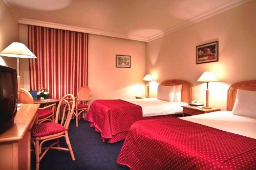a hotel room with two beds and a table and chairs at Ramada by Wyndham Sofia City Center in Sofia