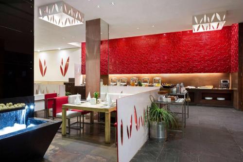 a restaurant with a red wall and tables and chairs at Ramada Ajmer in Kishangarh