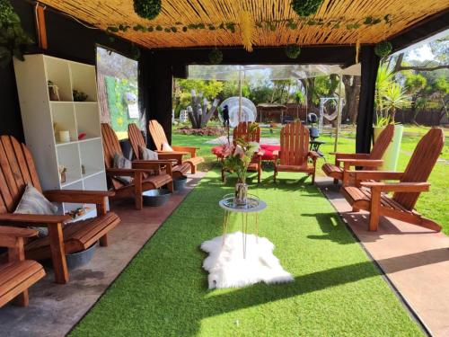 a patio with chairs and a table and grass at Pamensky Bush Lodge and Spa in Hartbeespoort