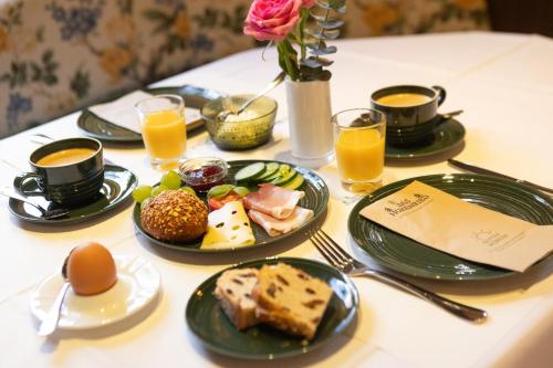 a table with plates of food and cups of orange juice at Das Hohenried in Freudenstadt
