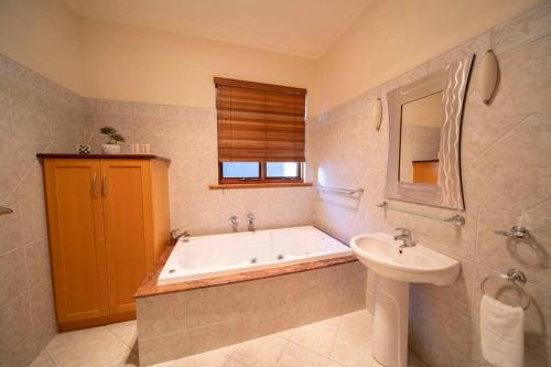 a bathroom with a bath tub and a sink at Cozy holiday home 5 mins walk to beach in Glenelg in Glenelg