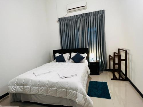 a bedroom with a large white bed with blue pillows at Cactus Piliyandala in Piliyandala