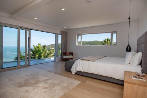 a bedroom with a large bed and large windows at Eagles Nest in Knysna