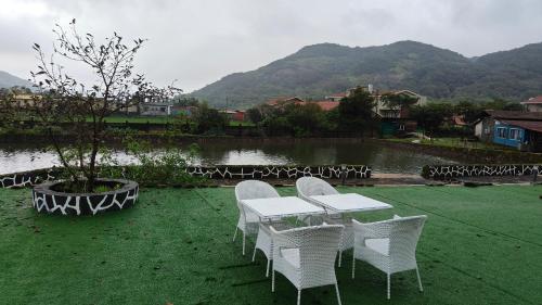 a group of white tables and chairs next to a lake at The Purple County - Homestay in Lonavala