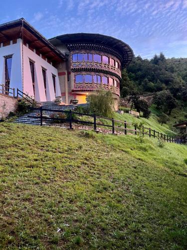 a large building on top of a grassy hill at Willing Resort, Trongsa in Kagha