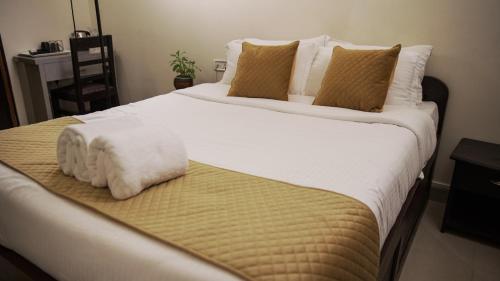 a large bed with white sheets and brown pillows at Ha Sharing in Shillong