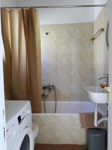 a bathroom with a tub and a sink and a washing machine at Lydias apartment in Panagioúda