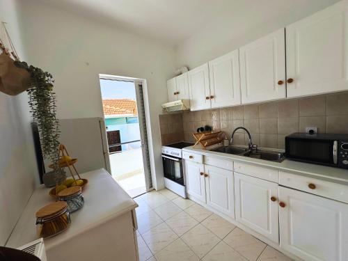 a kitchen with white cabinets and a sink and a stove at Lydias apartment in Panagioúda