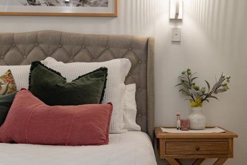 a bed with red and green pillows and a night stand at Airlie Breezes at the Boathouse in Airlie Beach
