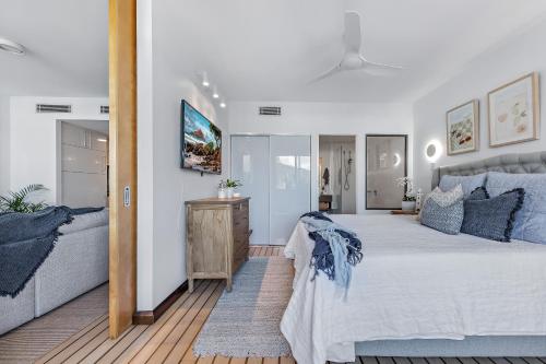 a bedroom with a large white bed with blue pillows at Airlie Breezes at the Boathouse in Airlie Beach