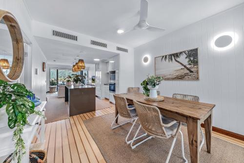 a kitchen and dining room with a wooden table and chairs at Airlie Breezes at the Boathouse in Airlie Beach