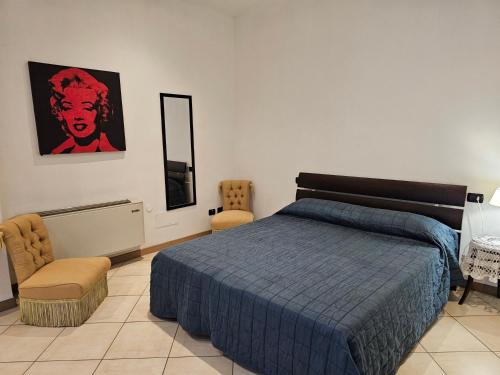 a bedroom with a bed with a blue comforter and chairs at Locazione turistica da Lena in Piacenza