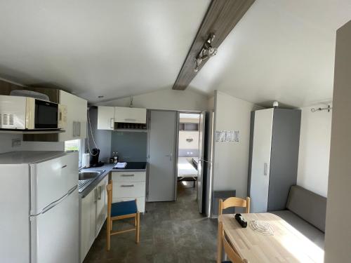 a kitchen with white cabinets and a table in a room at Le Riesling - Mobilhome pour 6 - TV - Climatisé in Boofzheim
