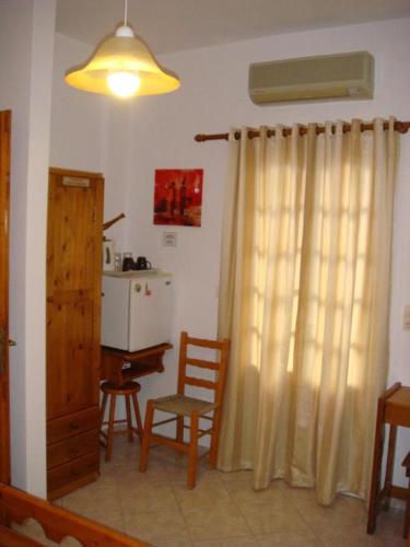 a living room with a curtain and a table and chair at Boussetil Rooms CapAnMat in Tinos Town