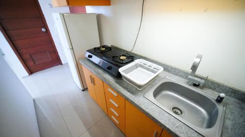 a kitchen with a sink and a stove at Strategic Studio Apartment at High Point Serviced By Travelio in Siwalapkerto