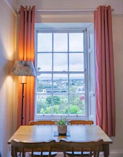 a dining room table with a large window at East Wing Apartment in Elgin in Elgin