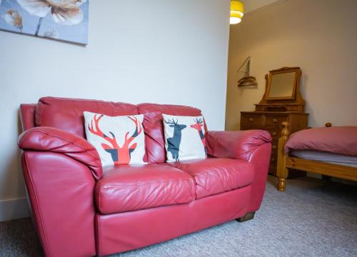 a red leather couch with two pillows on it at East Wing Apartment in Elgin in Elgin