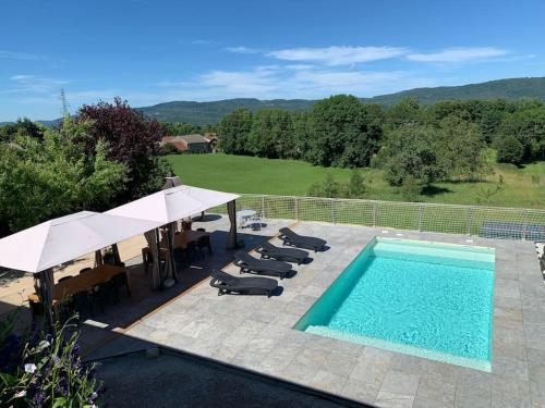 - une piscine bordée de parasols et de chaises longues dans l'établissement Gîte 5 chambres piscine vue montagne, à Ordonnaz