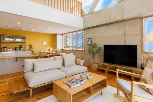 a living room with a couch and a flat screen tv at 沖縄市コザ サウナ付きBBQ可能 最大14名 飲食店多数 GBs house in Goya