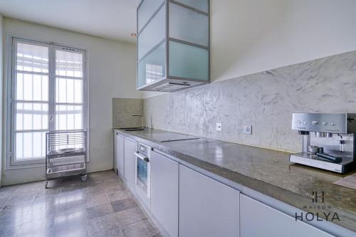 une cuisine avec des armoires blanches et un comptoir dans l'établissement Proche Opéra Garnier - Le Prestigieux - 247B, à Paris