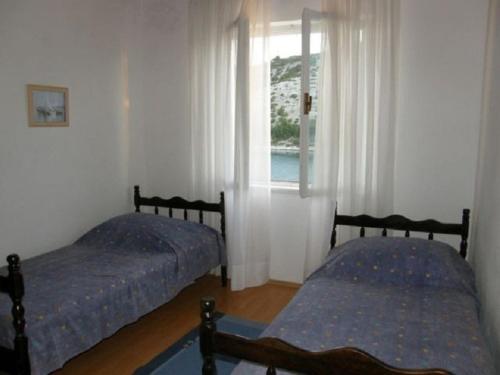 two beds in a room with a window at Apartments Rusulica in Vinišće