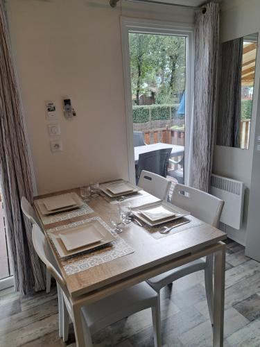 une salle à manger avec une table et des chaises et une fenêtre dans l'établissement Mobil home Domaine de la Forge, à La Teste-de-Buch