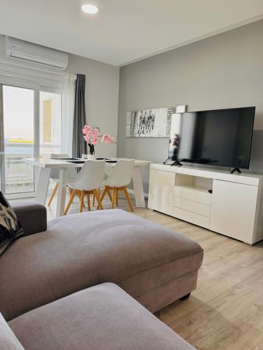 a living room with a couch and a tv and a table at Sea view 3 bedrooms apartment in Limassol