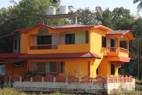 an orange house with a fence in front of it at Pramod Guesthouse in Guirim