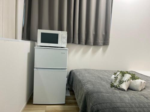 a room with a bed with a microwave and a tv at Ikebukuro Area R1 NishiikeApartment 5F No Elevator in Tokyo