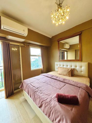 a bedroom with a large bed and a chandelier at Room Transit 3jam Apartemen Margonda Residence 2 By Younz Apartemen in Pondokcina