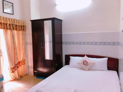 a bedroom with a white bed with a wooden headboard at Khách sạn Kim Phụng Ngân in Can Tho