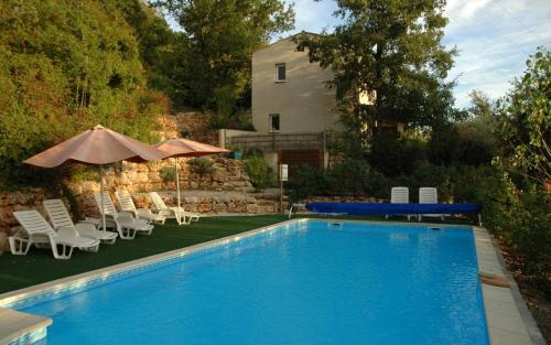 une piscine avec des chaises et un parasol ainsi qu'une maison dans l'établissement Gîte La résidence n°1, à Bauduen