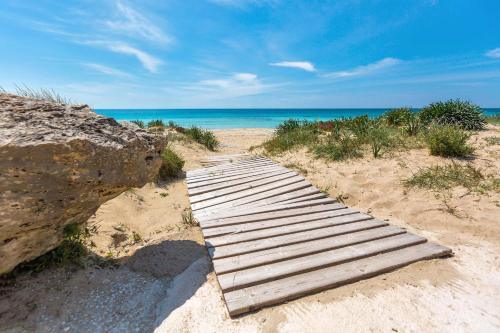 a wooden boardwalk in the sand on the beach at La Perla Bianca Luxury Spa by Perle di Puglia in Oria