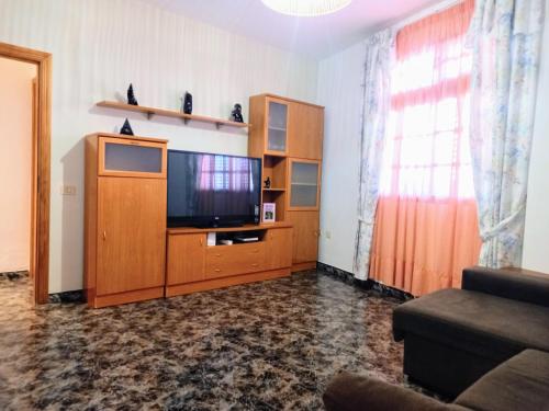 - un salon avec une télévision à écran plat dans un centre de divertissement en bois dans l'établissement Bonita casa cerca de la playa - Chalet Eras Costeras, à Las Eras