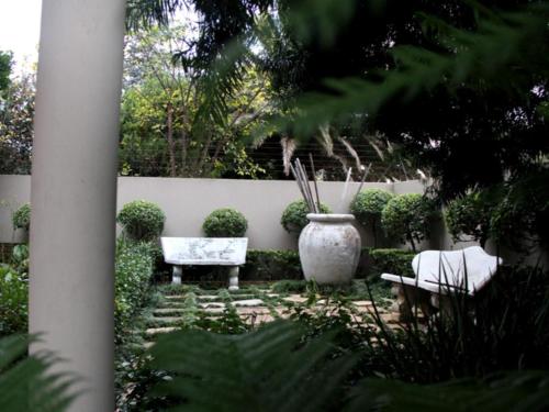 a garden with two chairs and a vase at Feathers Guest House in Middelburg