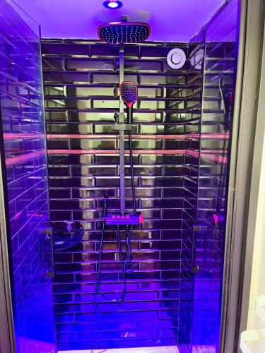 une douche avec un éclairage violet dans une salle de bain dans l'établissement Appartement en duplex proche gare d'Amiens, à Amiens