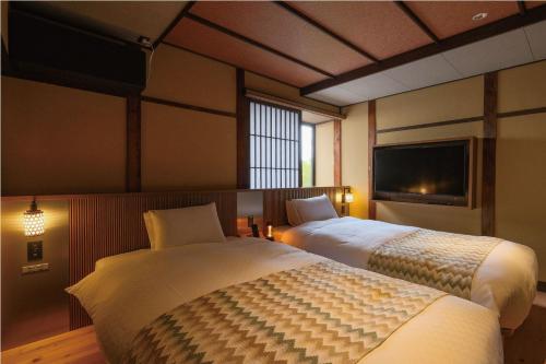 a bedroom with two beds and a television in it at Tomonoura Shiomachi Hotel in Fukuyama