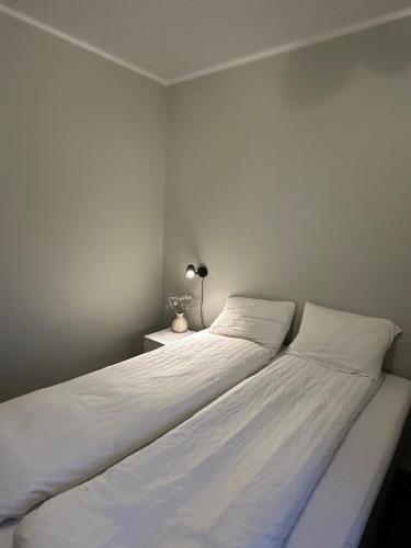 a bedroom with a bed with white sheets and a lamp at Apartment Solsiden Trondheim in Trondheim