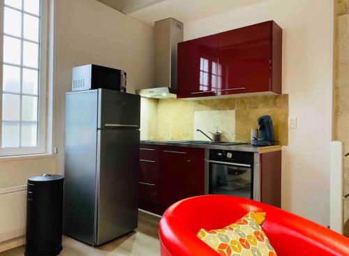 a kitchen with a red chair and a refrigerator at Le Quai 2, ancien Moulin au Bord de la Charente - Charme et Sérénité à Jarnac in Jarnac
