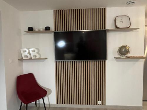 - une télévision murale avec une chaise et un réveil dans l'établissement T2 Troyes, à Troyes