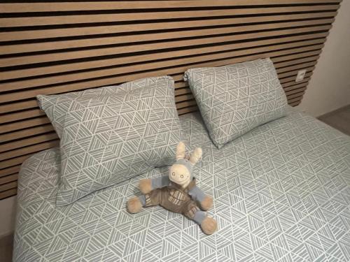 - un ours en peluche posé sur un lit avec deux oreillers dans l'établissement T2 Troyes, à Troyes