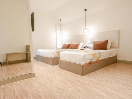a bedroom with two beds and a mirror at A Hotel Joo Chiat in Singapore