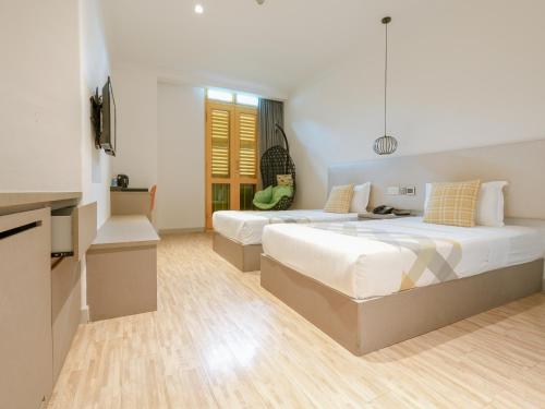 two beds in a large room with a kitchen and a kitchen at A Hotel Joo Chiat in Singapore