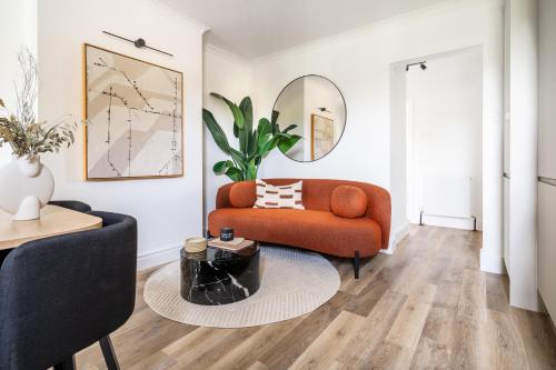 a living room with a orange couch and a table at Newly Designed, 2br Apt, 5min from Northwood London Tube Station, NATO HQ, Ideal for Wembley, Warner Studio, Contractors in Northwood