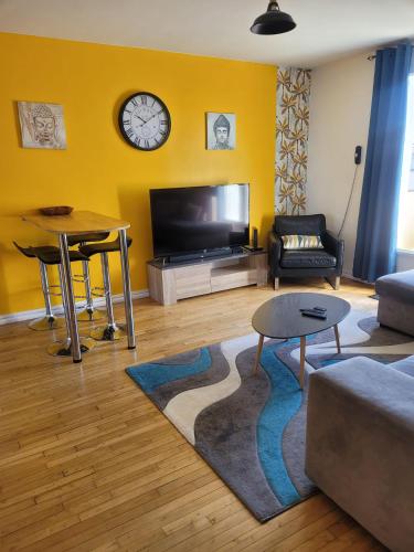 un salon avec un canapé et une horloge au mur dans l'établissement Appartement Eblé tout confort, à Angers