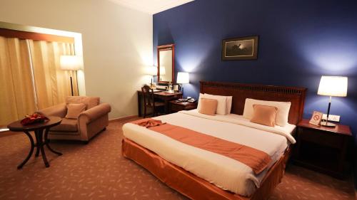 a hotel room with a bed and a chair at MGM Mark Whitefield in Bengaluru