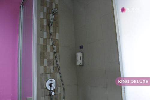 a shower with a shower head in a bathroom at Shakti Hotel Bandung in Bandung